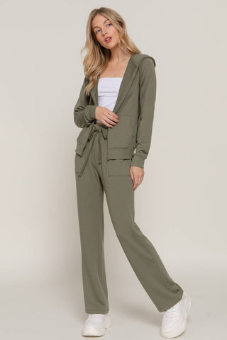 Woman wearing a green jumpsuit with a white top on a plain background