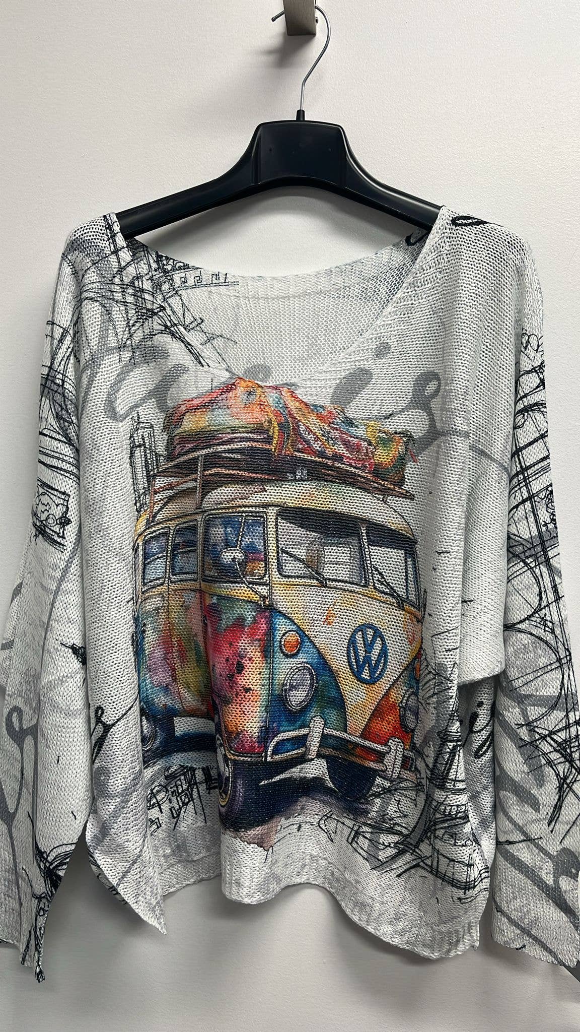 Sweater with a colorful Volkswagen bus design on a hanger against a white background