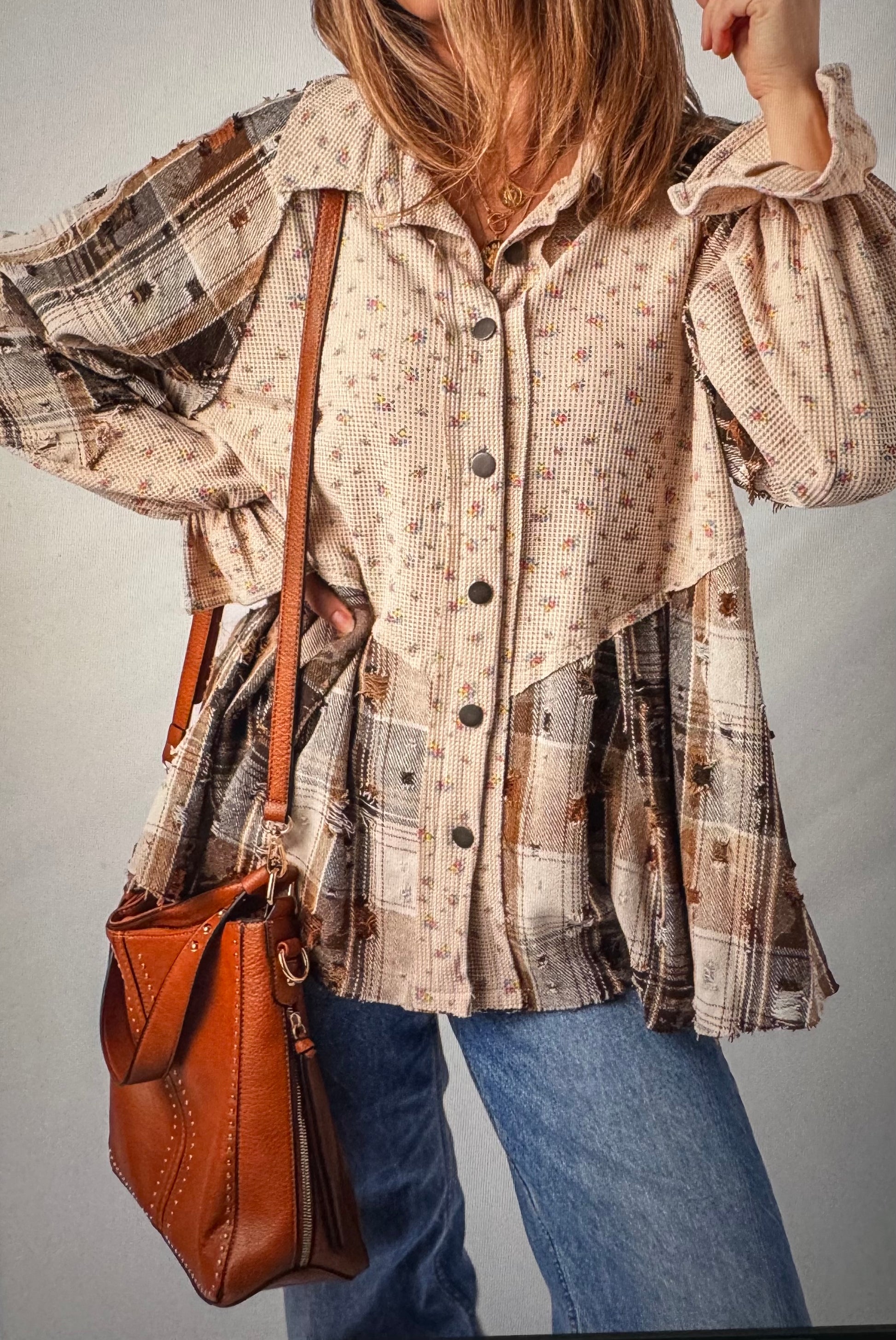 Person wearing a plaid shirt with a brown leather bag on a plain background