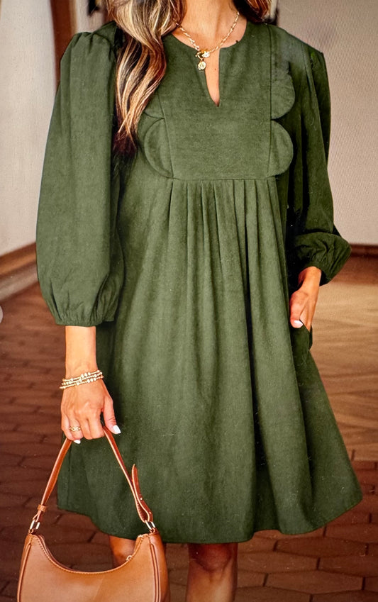 Green dress worn by a person with a brown handbag indoors.