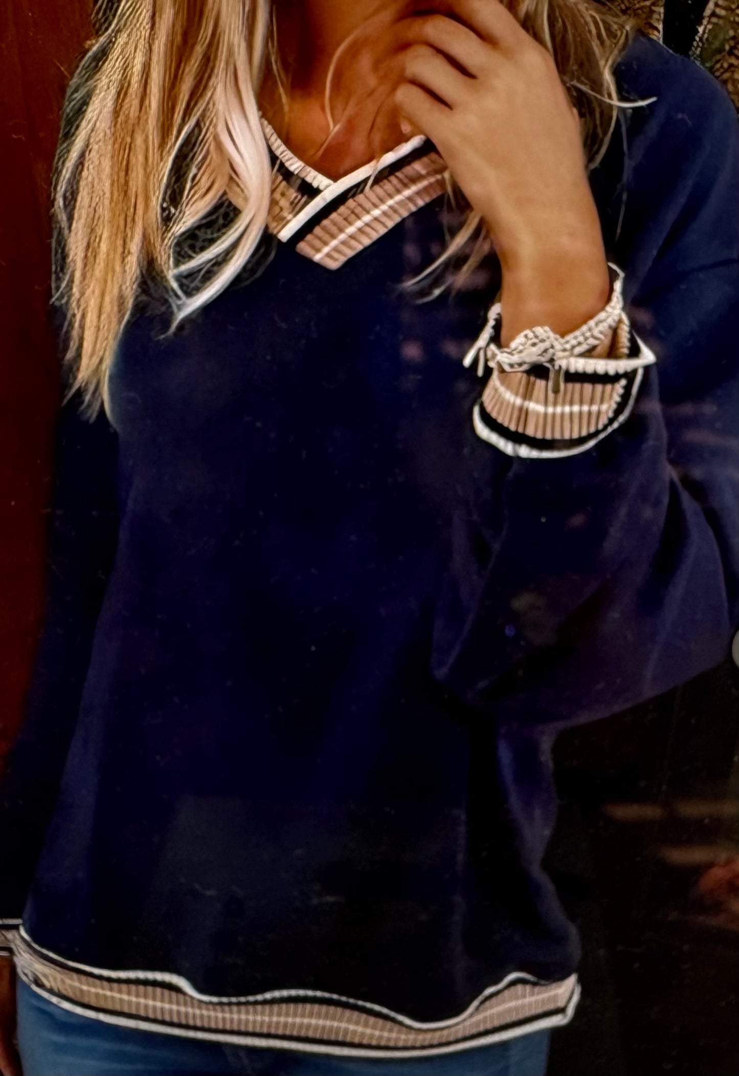 Person wearing a navy blue sweater with white and beige trim