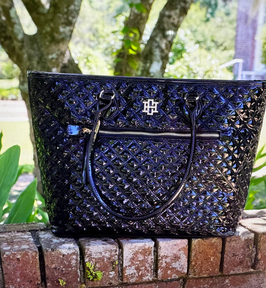 Black textured handbag with a brand logo on a brick ledge outdoors