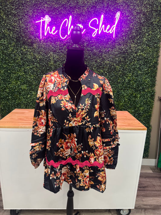 Floral top on a mannequin against a green wall with 'The Chic Shed"' sign.