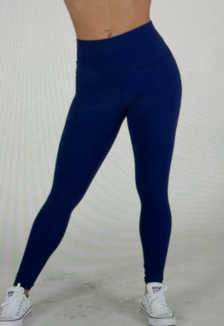 Model in blue leggings standing in front of a light colored wall