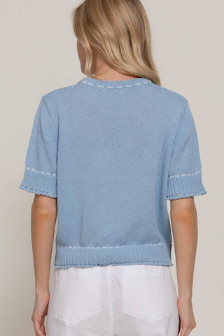 Light blue knitted top worn by a person on a plain background