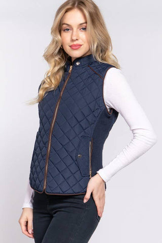 Woman wearing a navy quilted vest on a white background